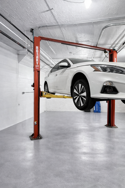 Rotary two-post lift raised with vehicle, front three-quarter view