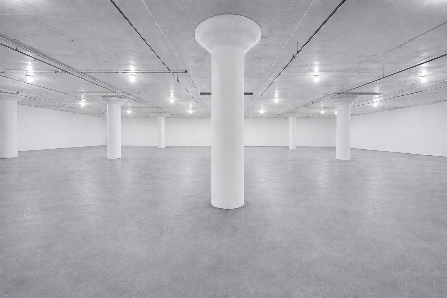 Wide view of indoor vehicle storage area showing full column row and ceiling lights